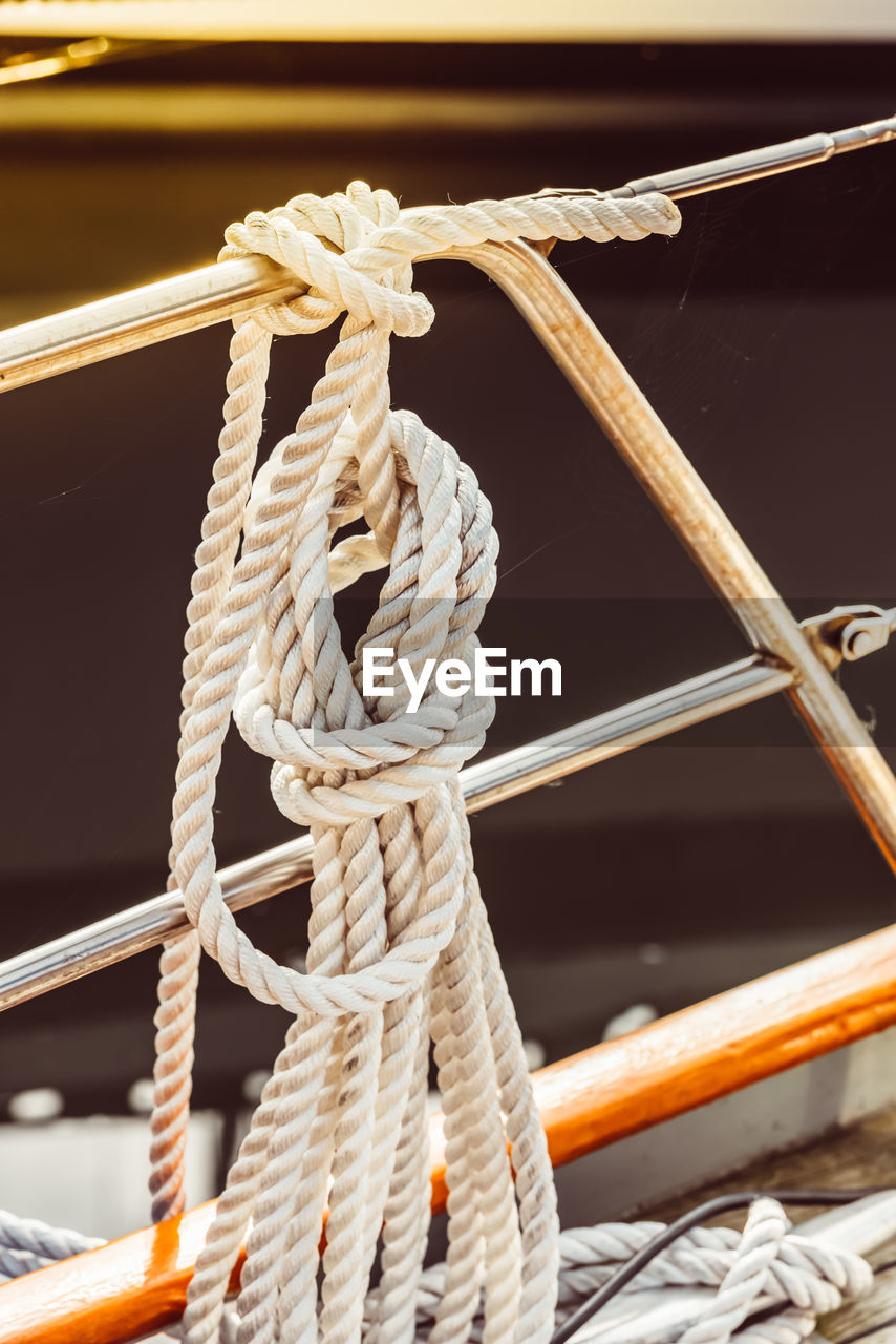 CLOSE-UP OF ROPE TIED ON WOODEN RAILING