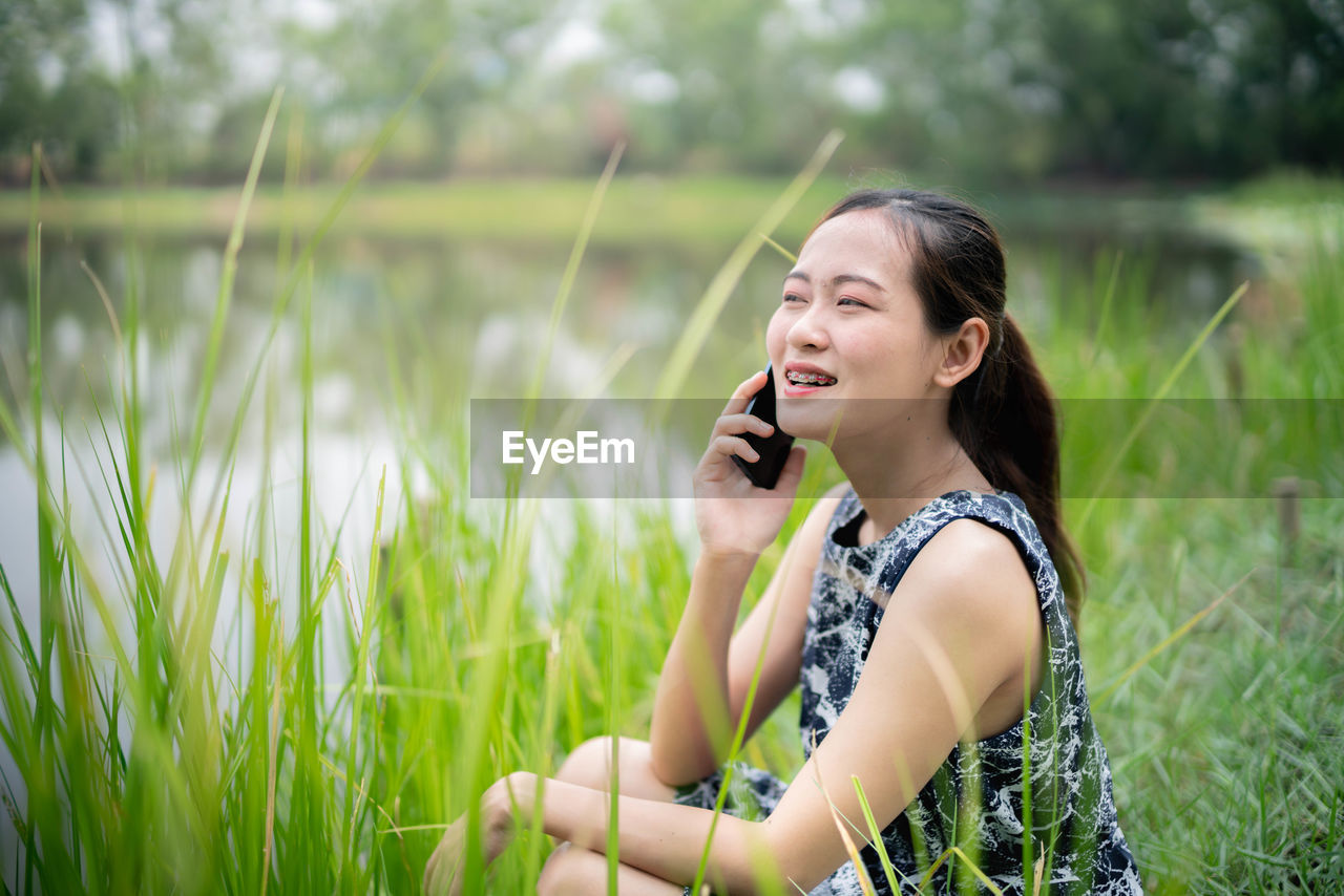 YOUNG WOMAN USING MOBILE PHONE IN FIELD