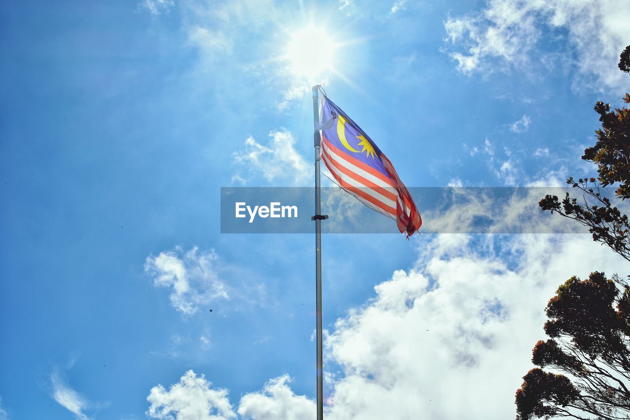 Low angle view of flag against sky on sunny day