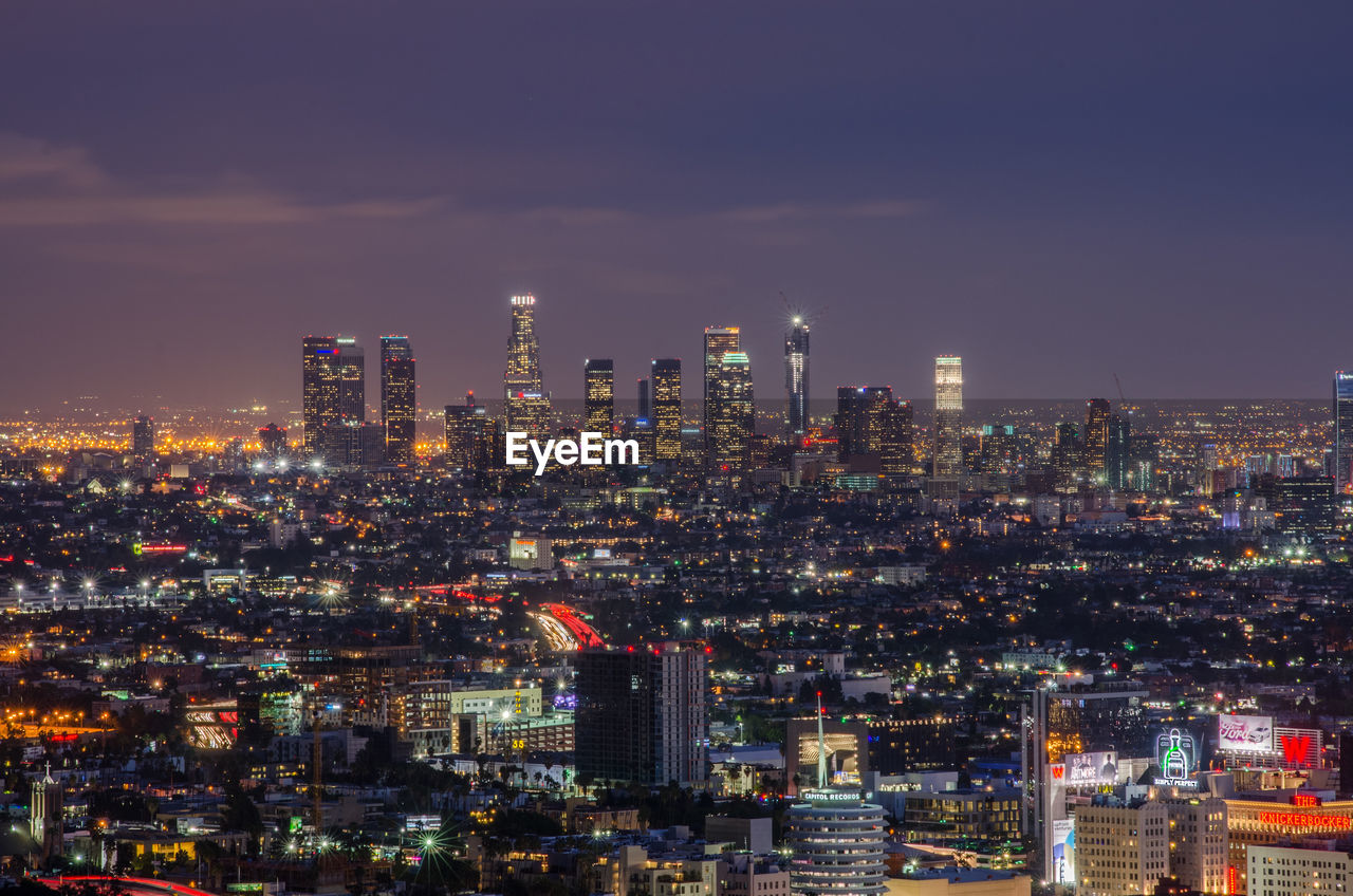 Illuminated cityscape against sky at night