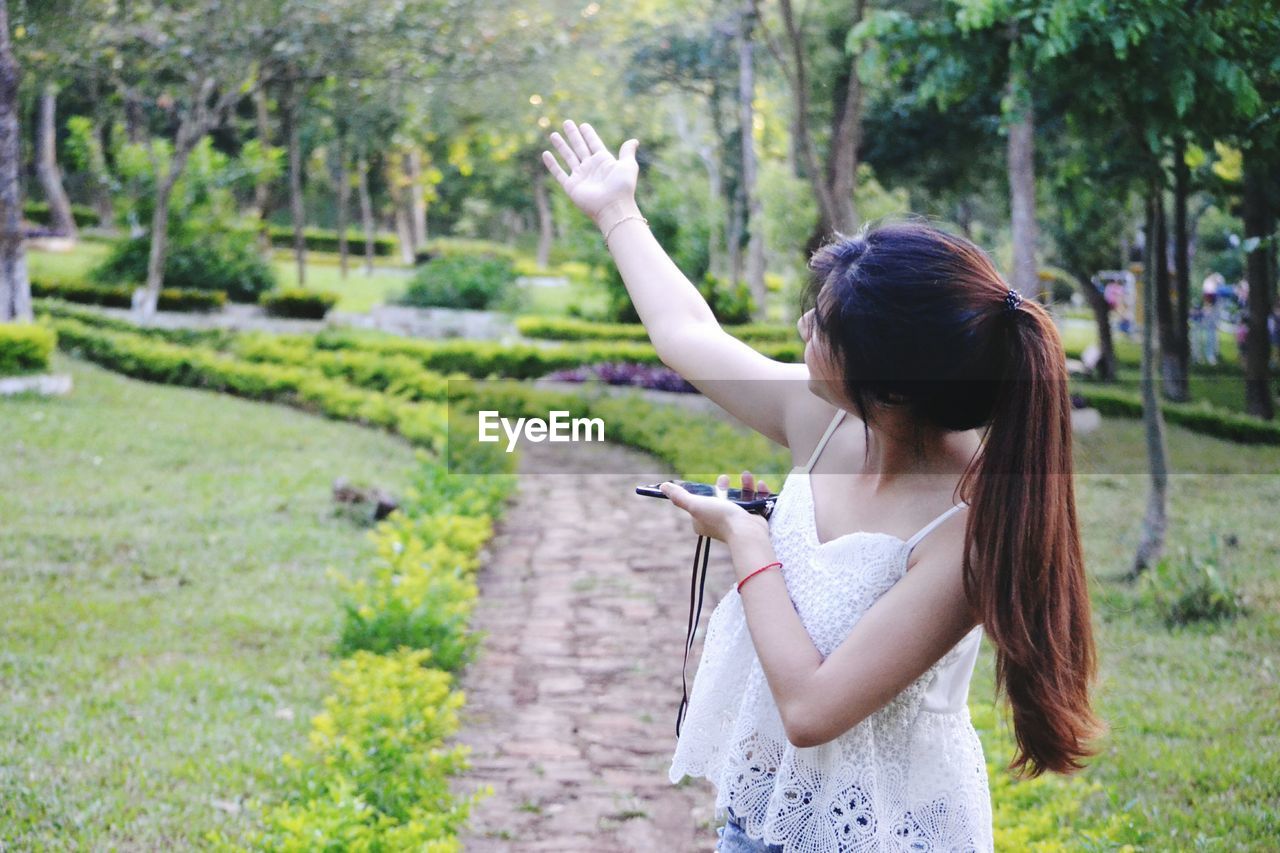 Woman with arms raised standing at park