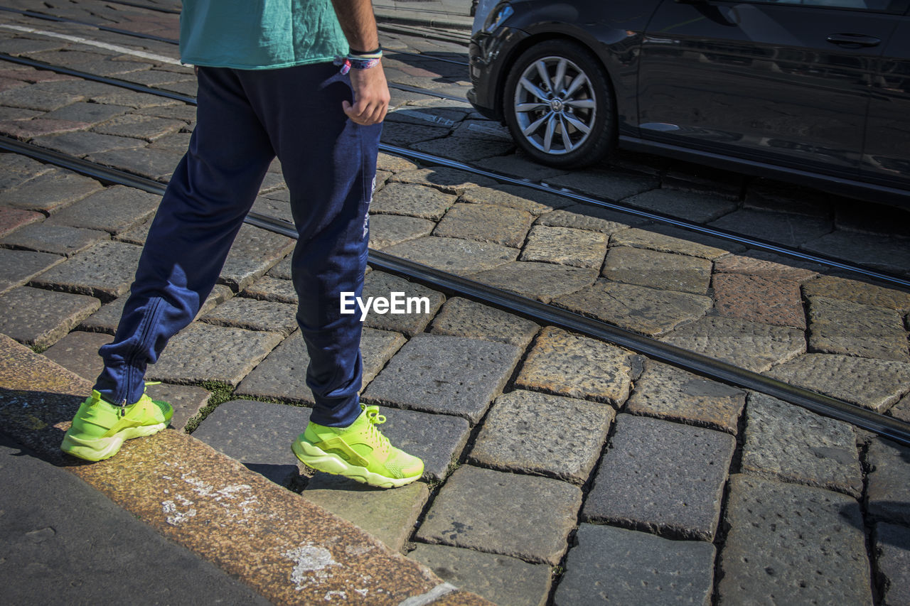 LOW SECTION OF MAN STANDING ON COBBLESTONE