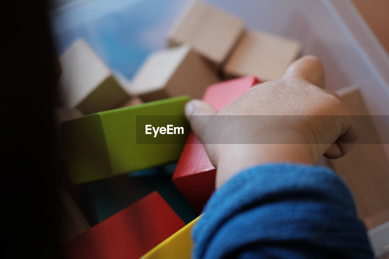 Cropped image of kid playing with toy blocks at home