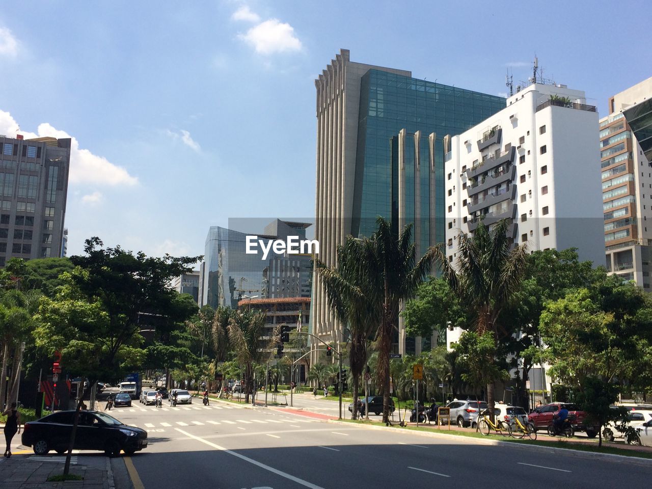 City street by modern buildings against sky