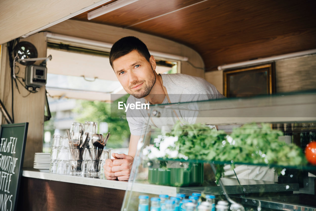 Portrait of male owner standing in food truck