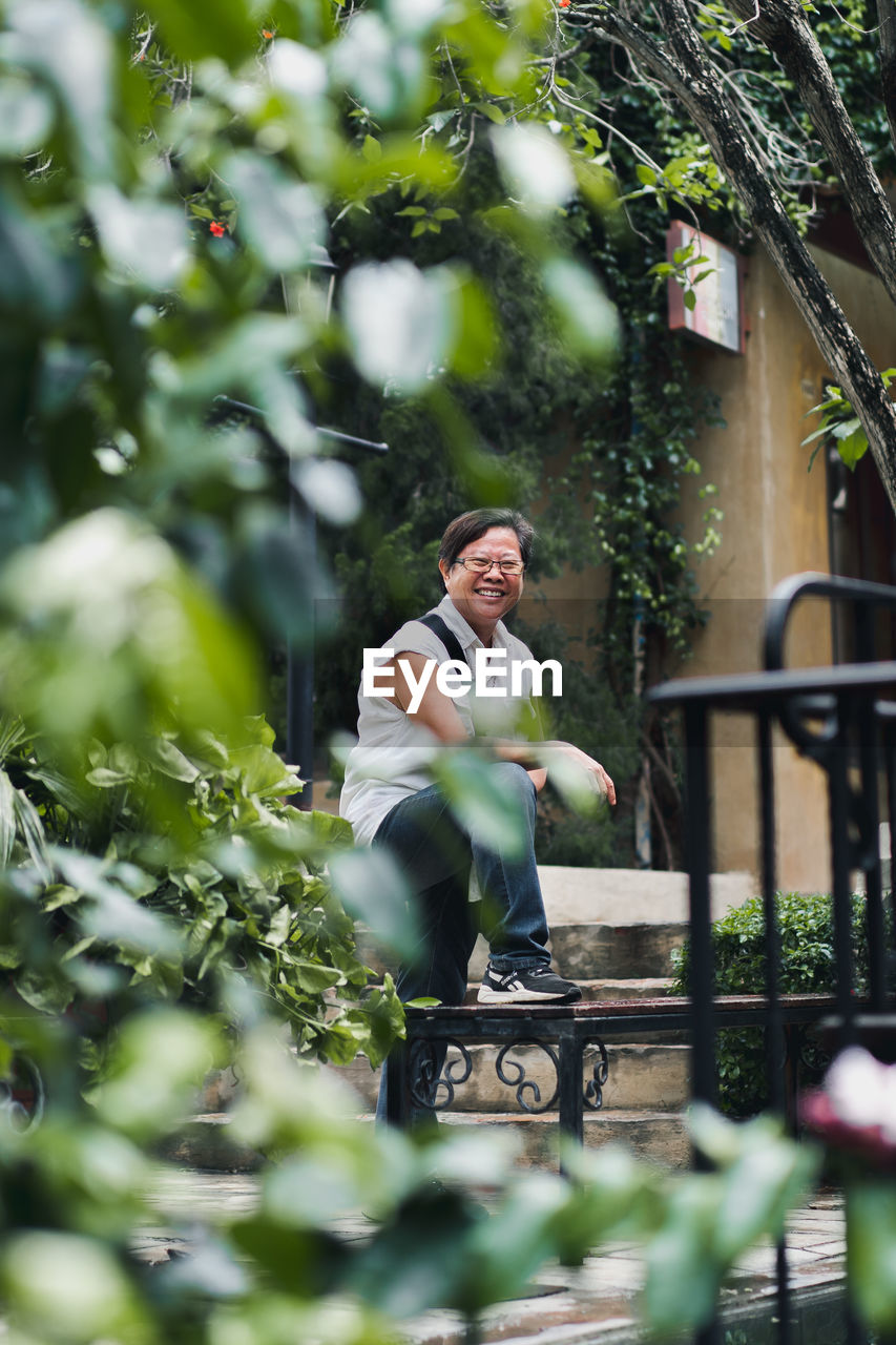 Portrait of smiling woman standing by plants in city