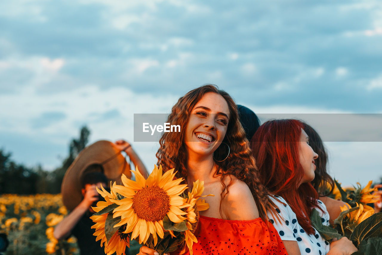 PORTRAIT OF A SMILING YOUNG WOMAN AGAINST SKY