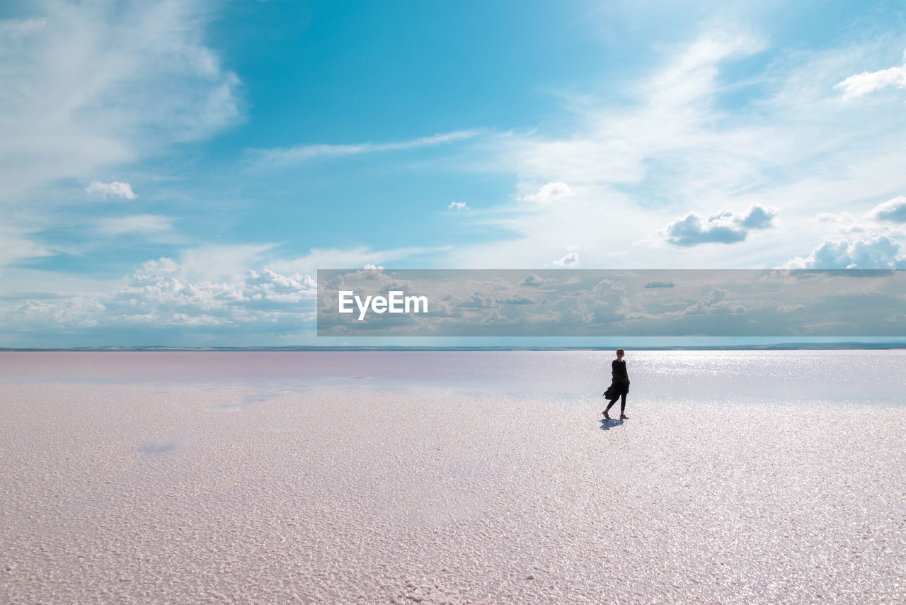 Woman at beach against sky during sunny day