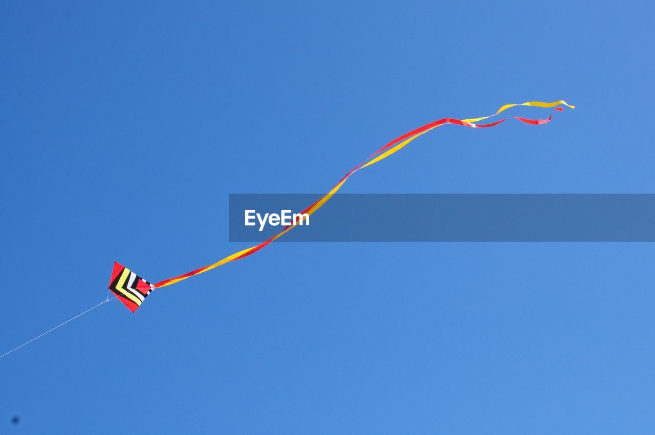 Low angle view of kite flying against clear blue sky