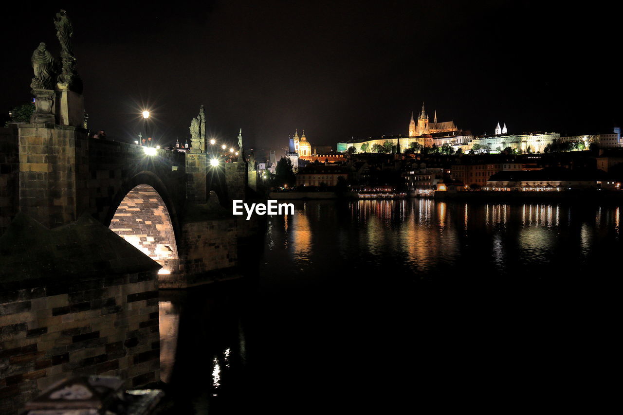 RIVER BY ILLUMINATED BUILDINGS AGAINST SKY AT NIGHT