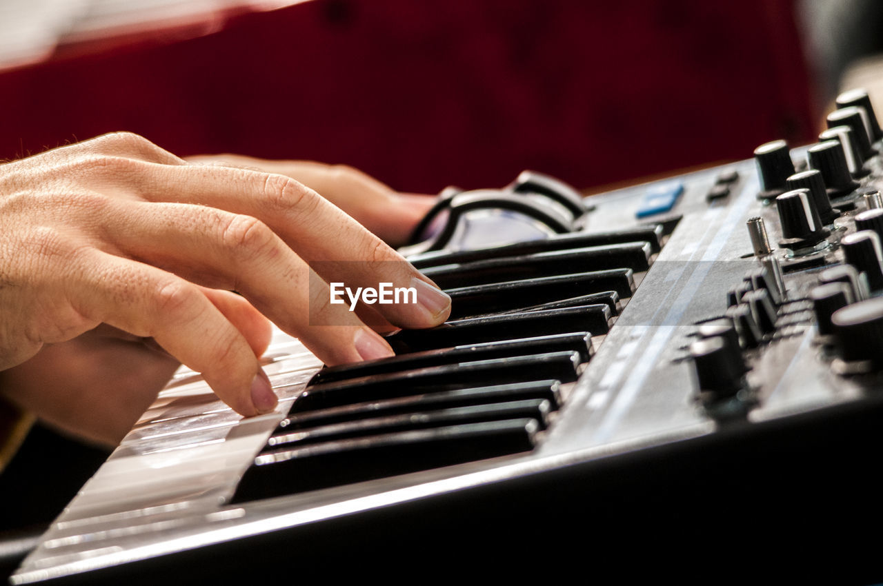 CLOSE-UP OF HAND PLAYING PIANO AT KEYS