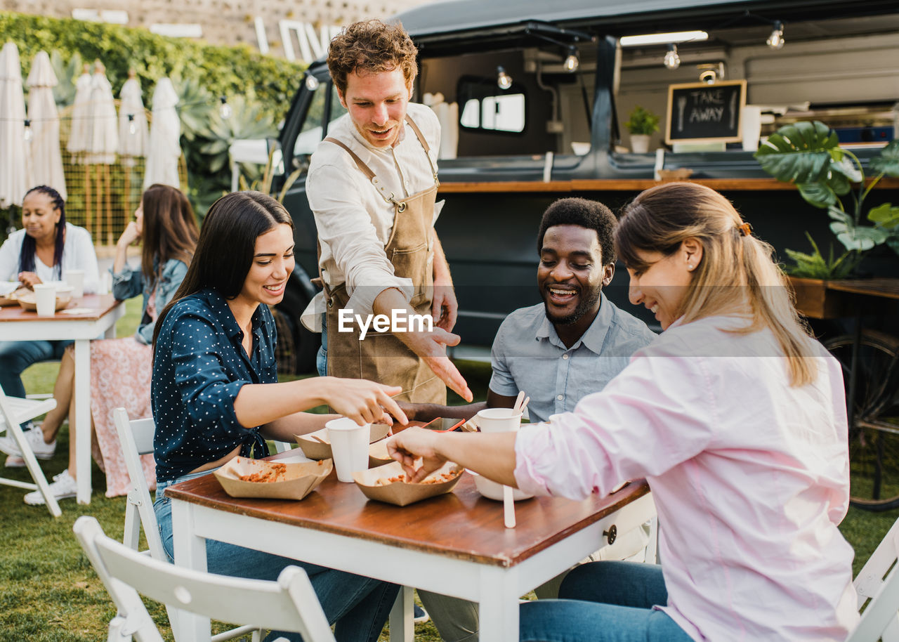 Smiling friends enjoying food at yard