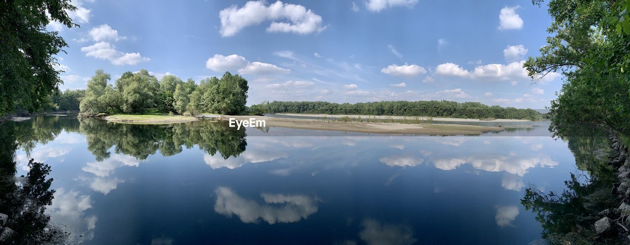 REFLECTION OF TREES IN LAKE AGAINST SKY