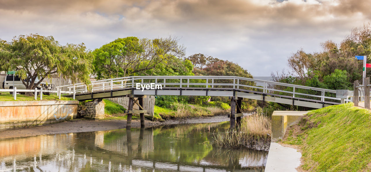 BRIDGE OVER RIVER BY TREES AGAINST SKY