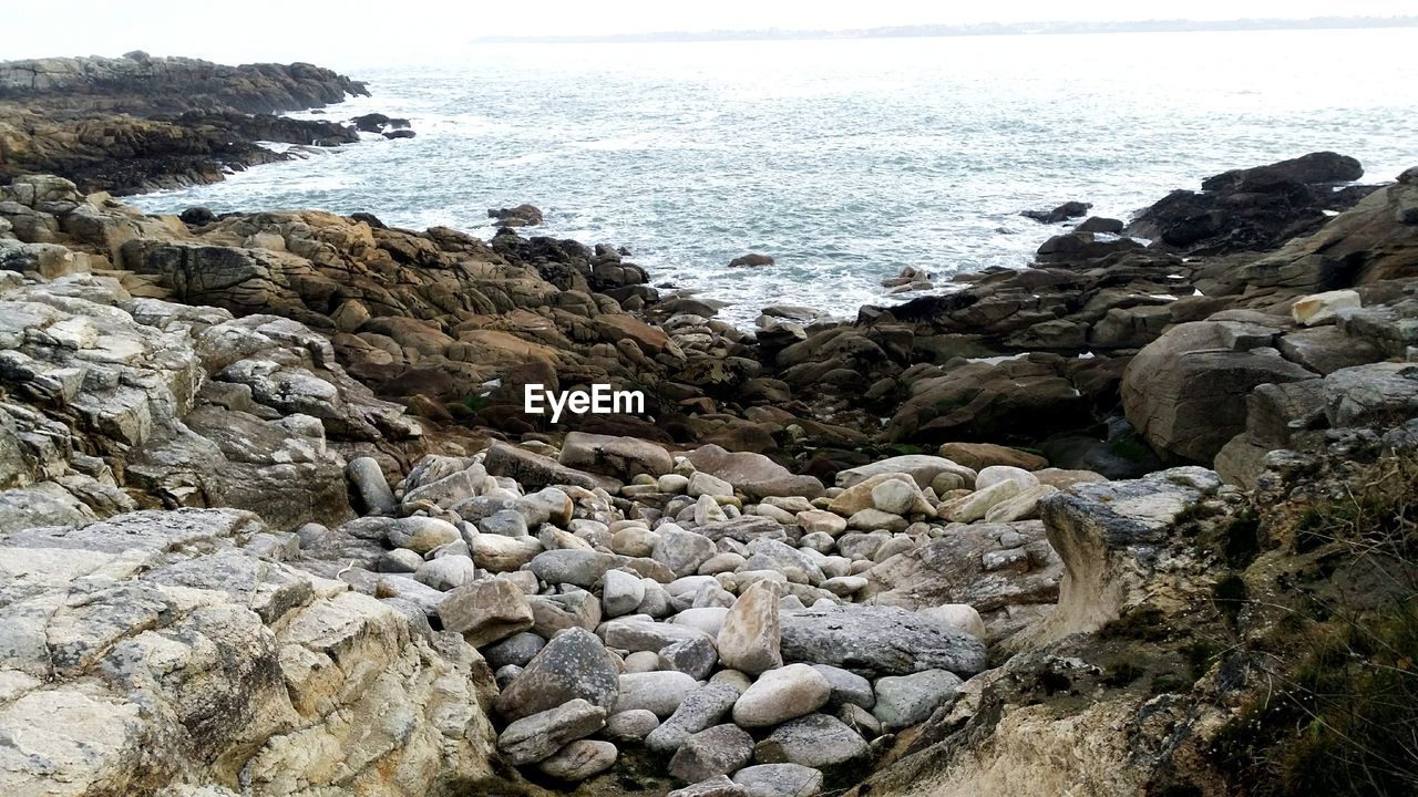 Rocks by sea against sky