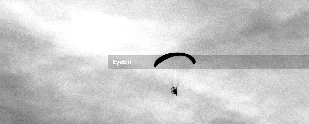 Low angle view of person paragliding against sky