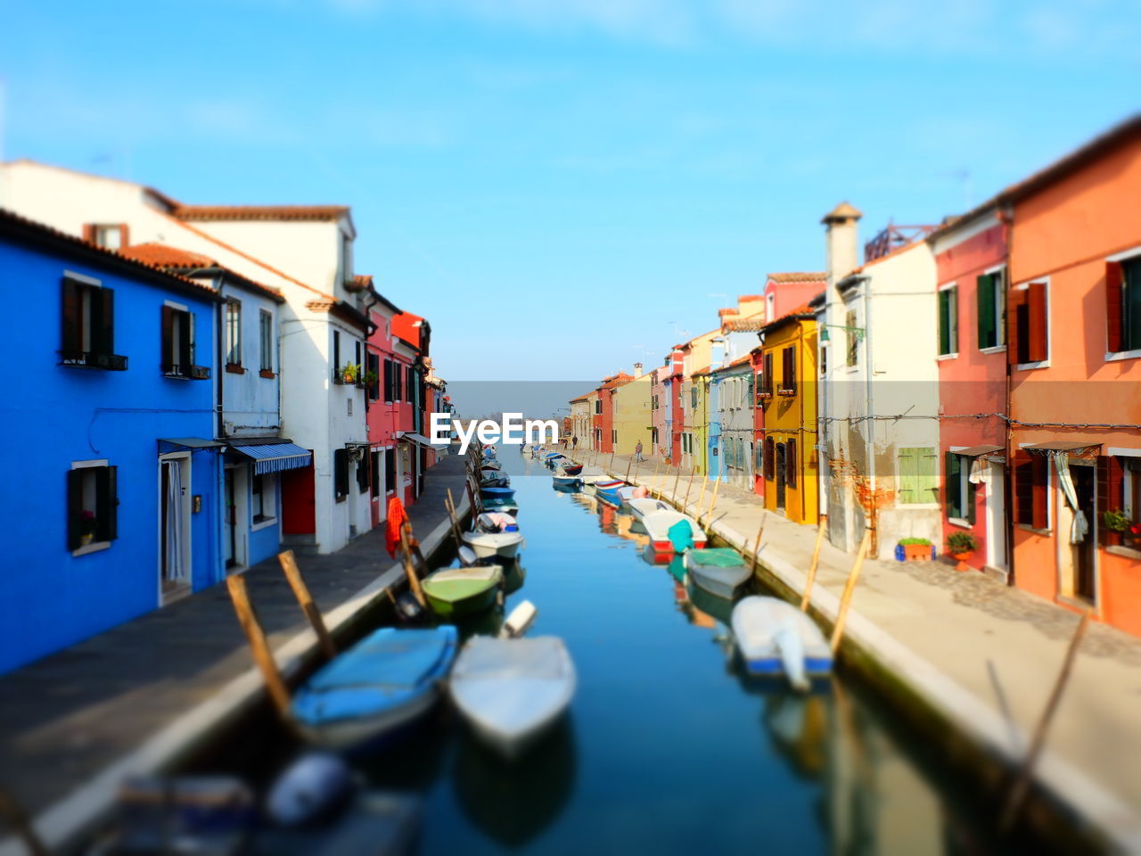 BOATS MOORED IN CANAL AMIDST BUILDINGS AGAINST BLUE SKY