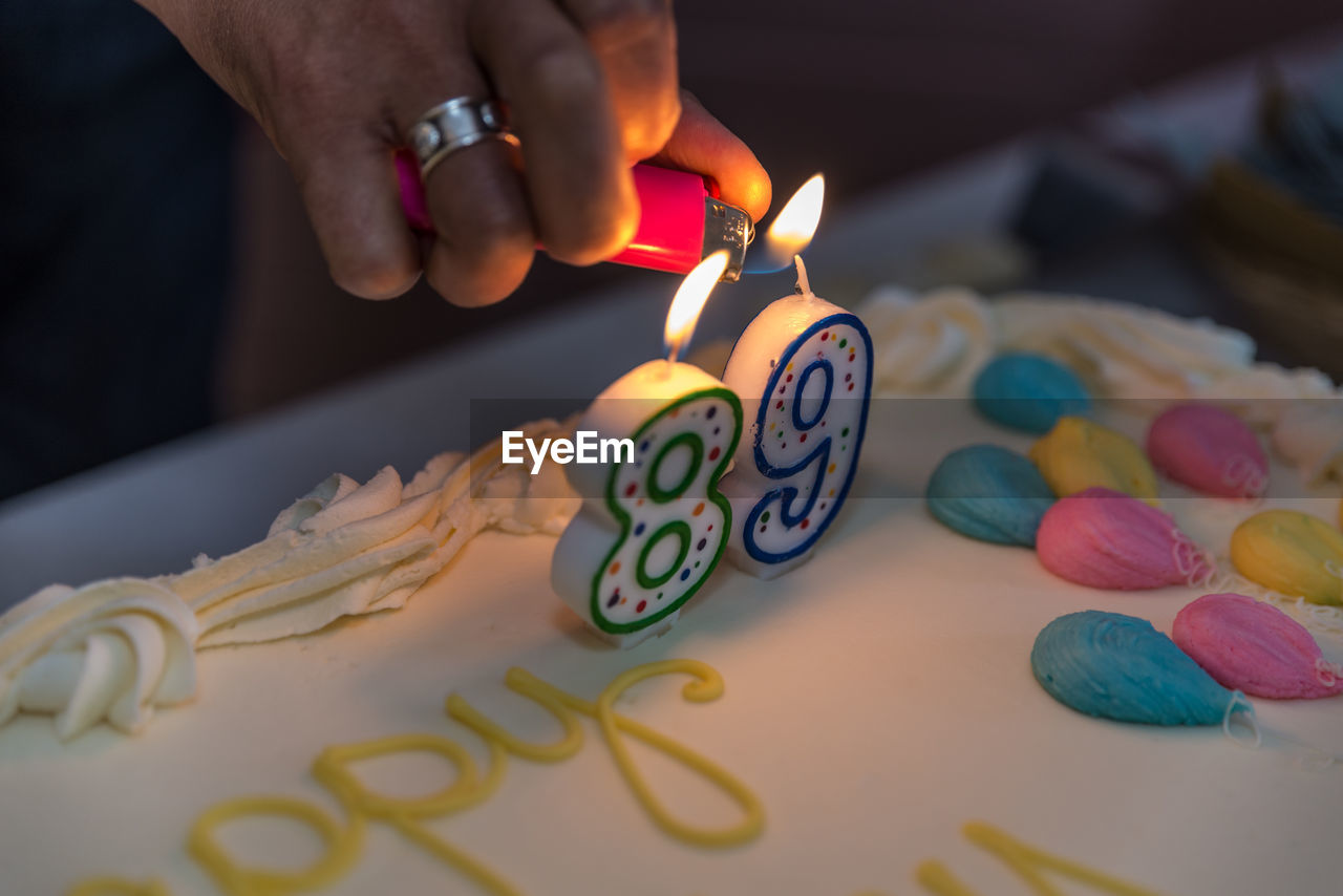 Human hand lighting candle on cake
