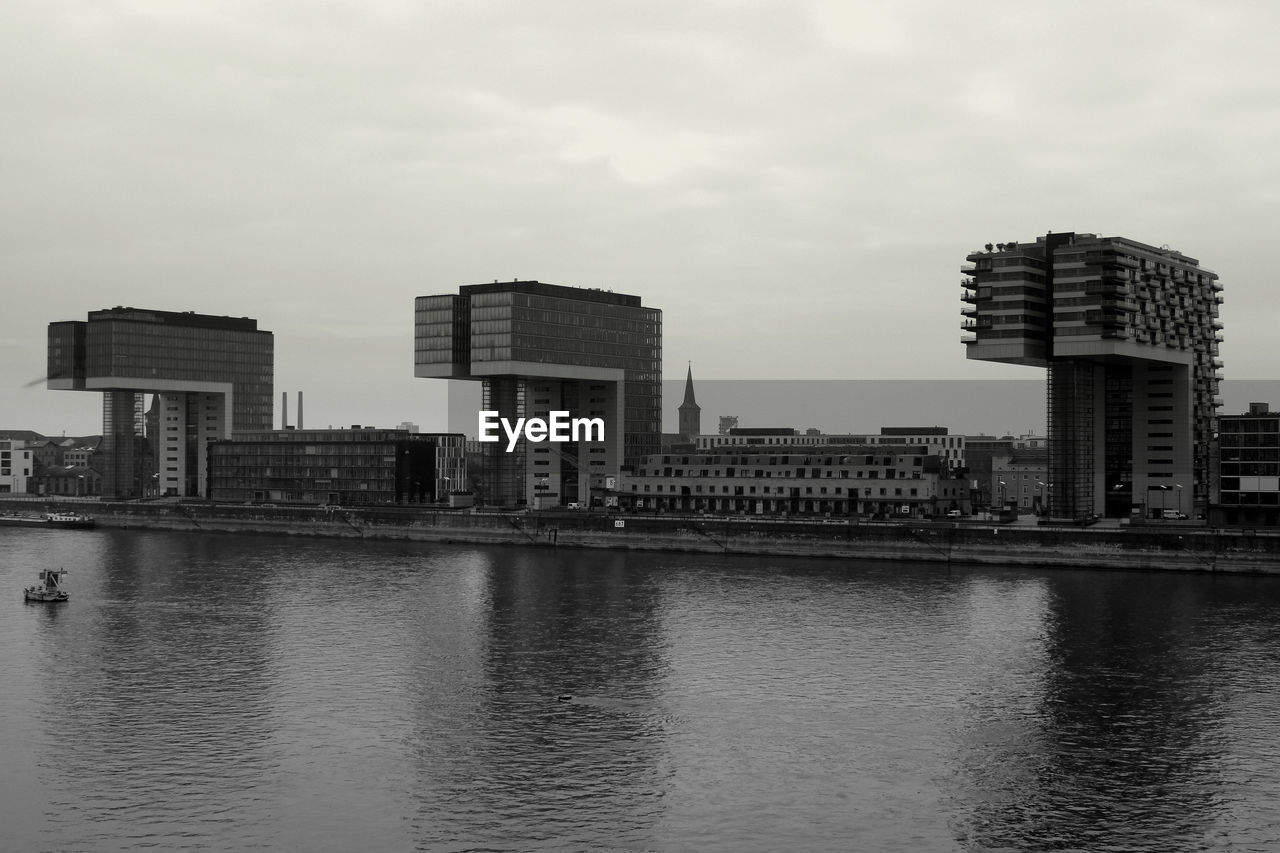 BUILDINGS BY RIVER AGAINST SKY