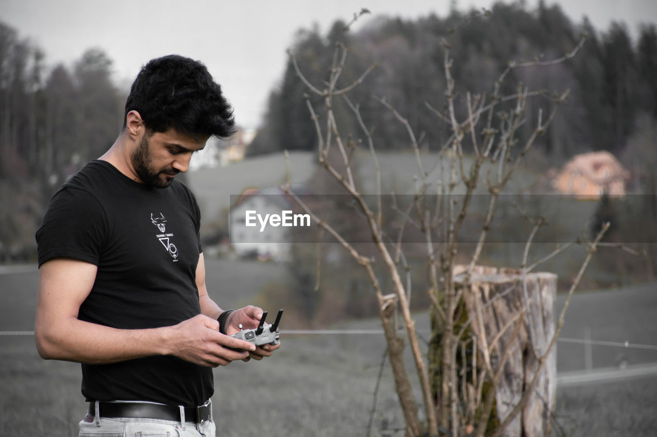 Side view of young man holding dji mini pro 4 controller 