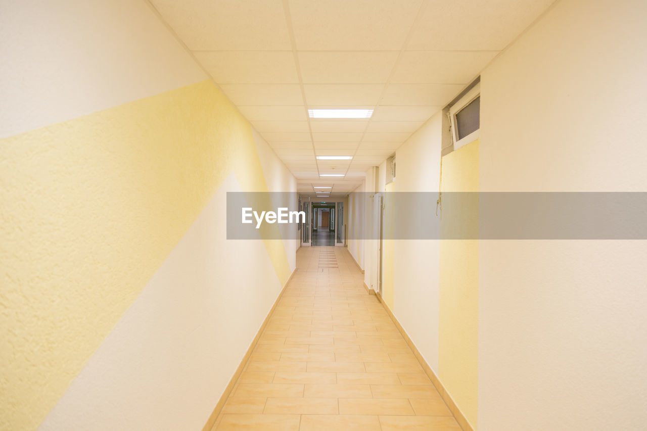 EMPTY CORRIDOR ALONG ILLUMINATED BUILDING