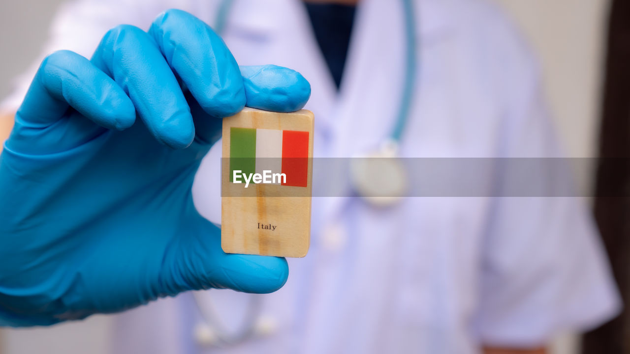 Midsection of doctor holding wood with italian flag