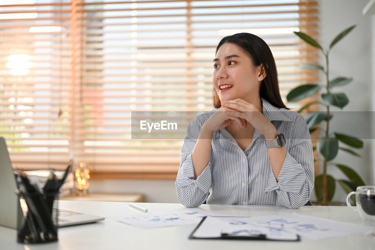 portrait of young woman using mobile phone while sitting at office