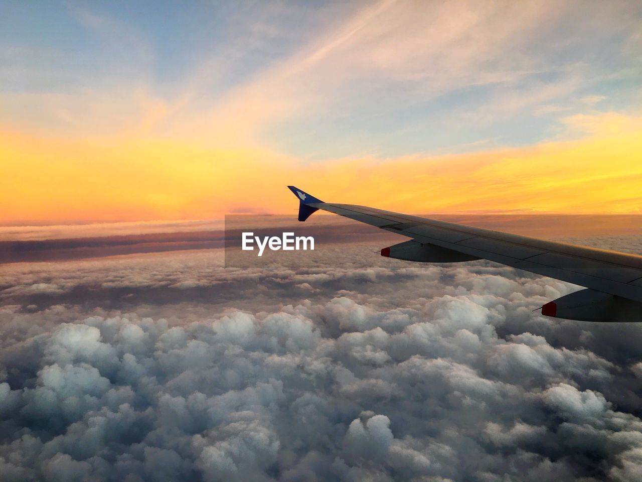 AIRPLANE FLYING OVER CLOUDSCAPE AGAINST SKY