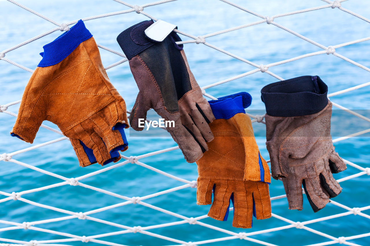 Gloves hanging on fence against sea