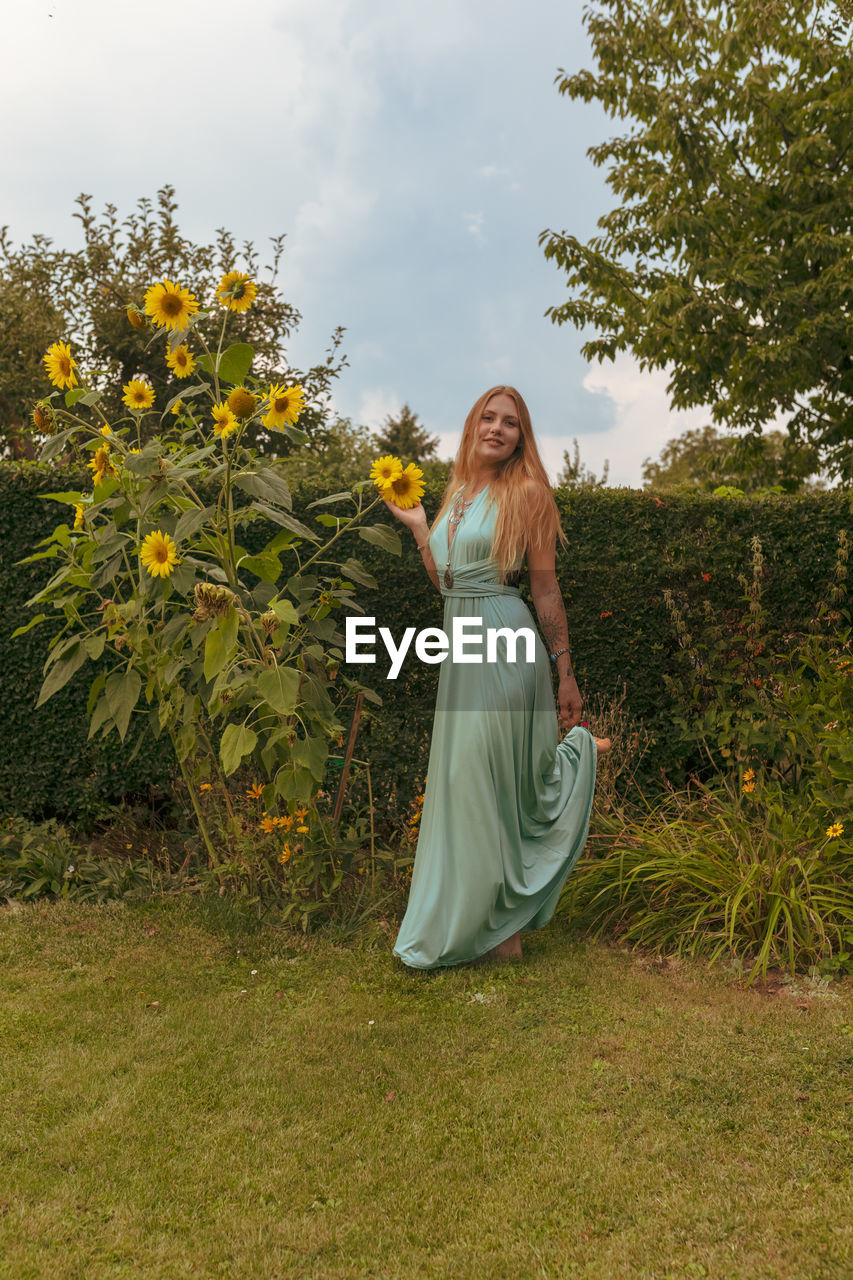 Portrait of smiling woman standing by flowering plant