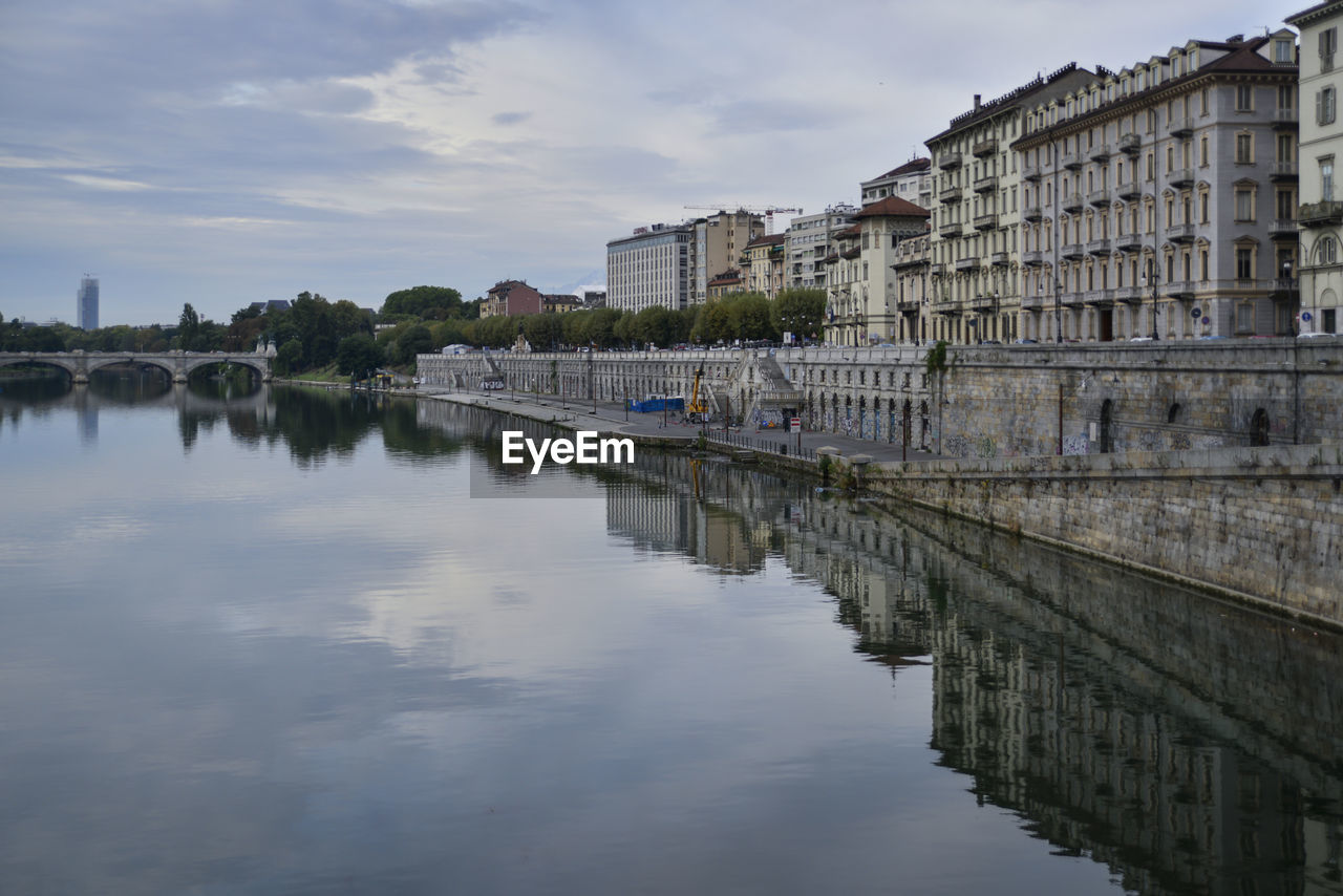 Buildings by river against sky in city