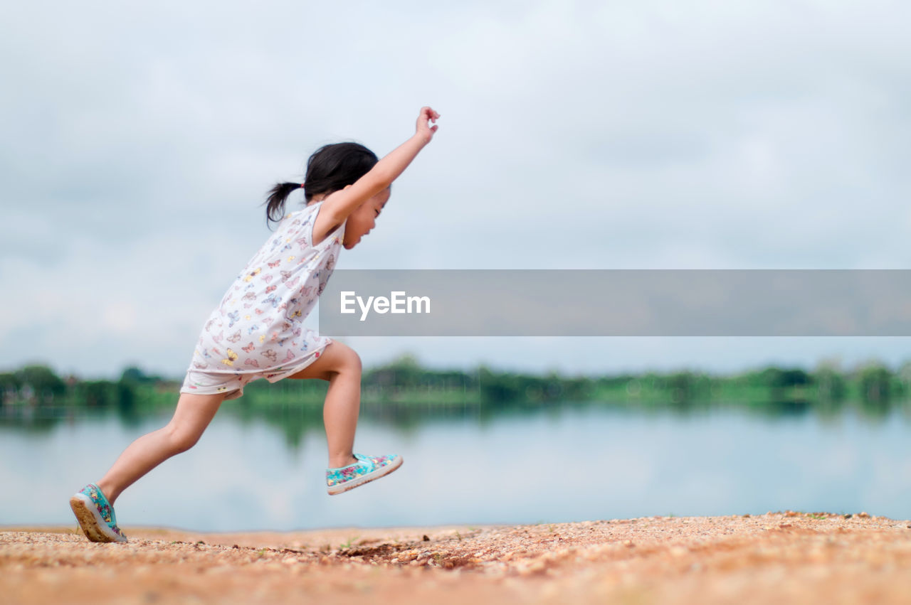 Girl running on field by river