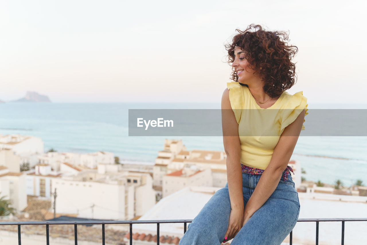 Young woman looking at sea against sky