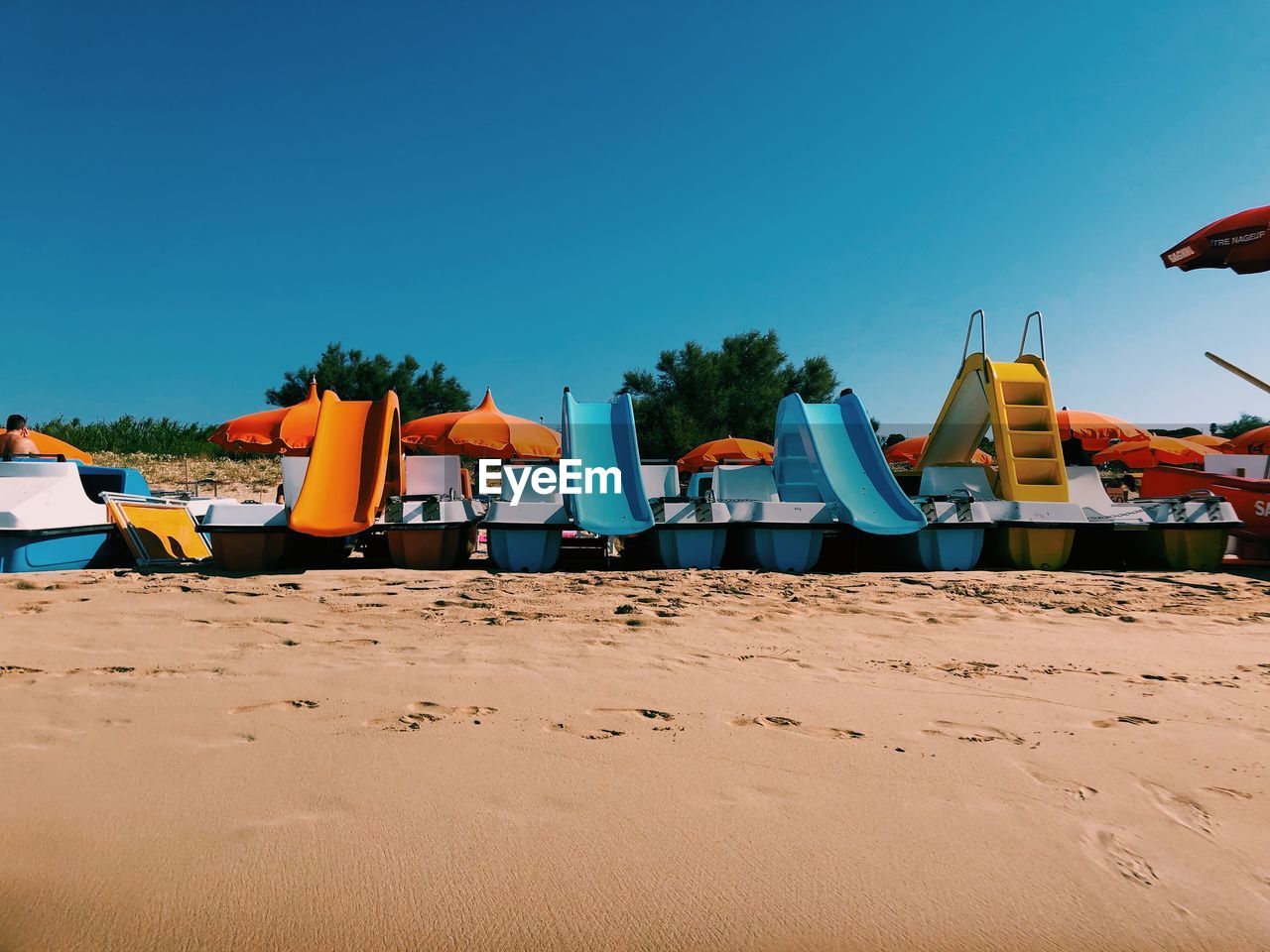 Leisure boats on beach against clear blue sky