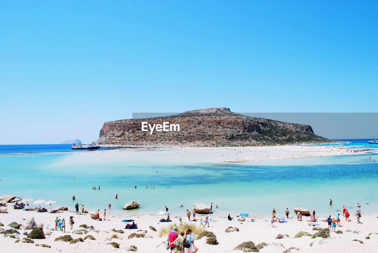 PEOPLE AT BEACH AGAINST CLEAR BLUE SKY