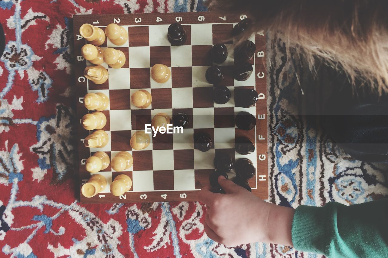 Cropped hand playing chess on bed