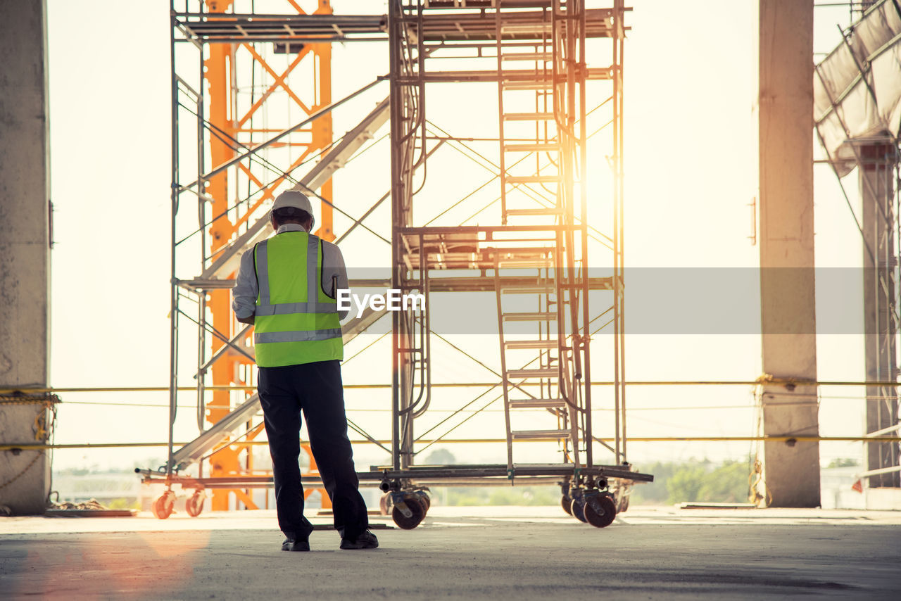 Rear view of manual worker standing at construction site