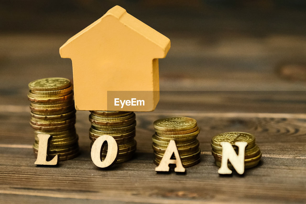 Close-up of coins with model home and loan text on table