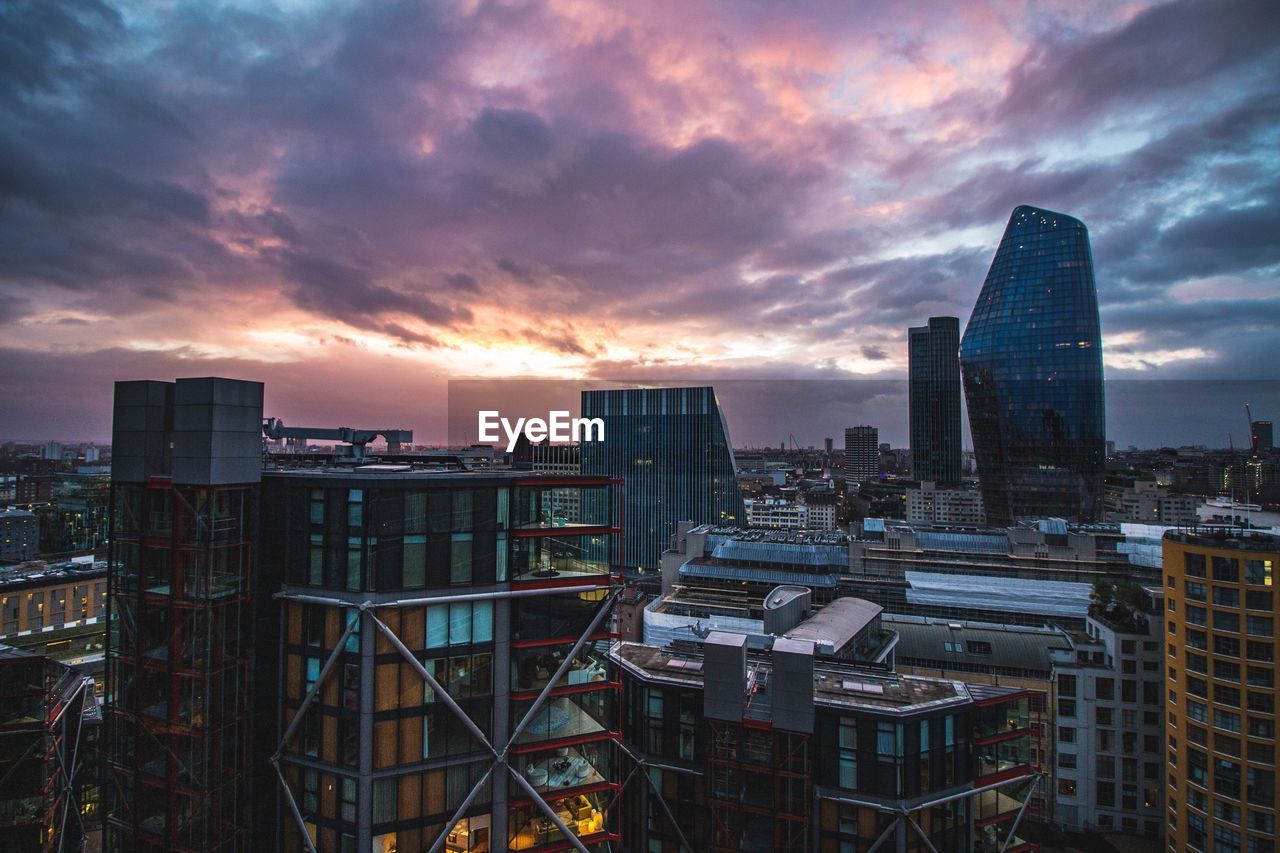 Modern buildings in city against sky at sunset