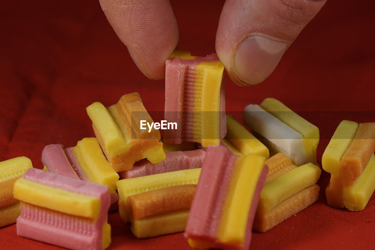 Cropped hand holding candy over red fabric