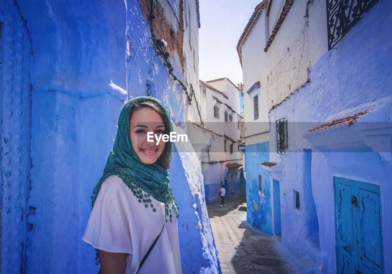 "The Blue City" We travelled from Sevilla to Tarifa, then took a ferry to Tangier, then a taxi to Chefchaouen, Morocco. EyeEmNewHere a new beginning Chefchaouen Morocco Beauty Blue City Blue Medina Looking At Camera Portrait One Person Young Women Young Adult Women Headscarf Beautiful Woman Scarf Front View Lifestyles Outdoors Day Smiling Leisure Activity Happiness Built Structure Digital Nomad Standing Building Exterior Warm Clothing Real People Clothing