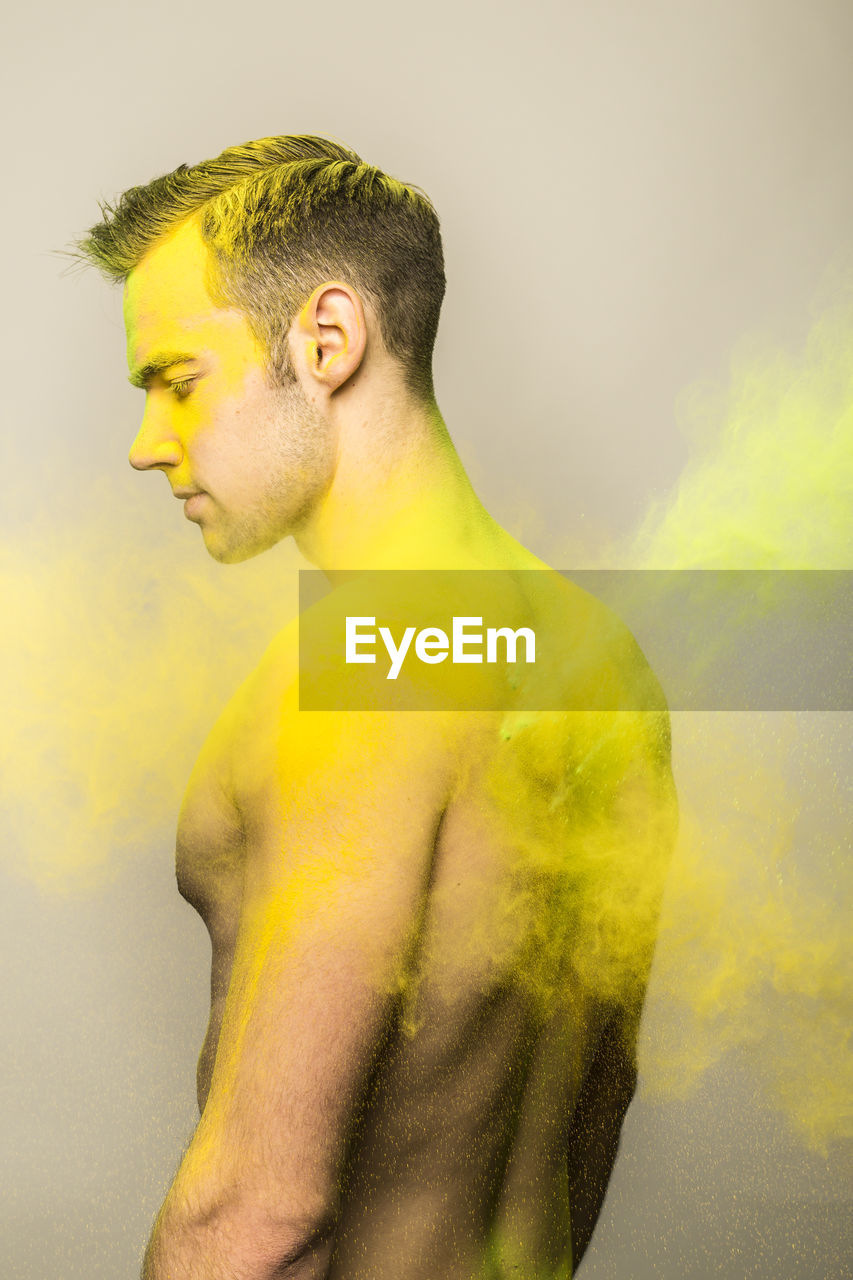 CLOSE-UP OF YOUNG MAN AGAINST YELLOW BACKGROUND