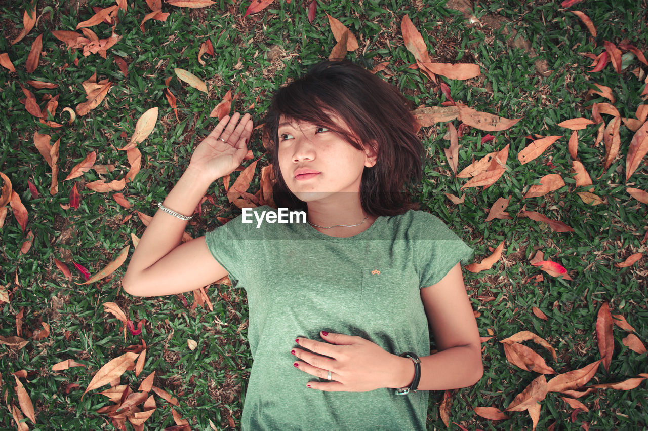 High angle view of young woman lying on field during autumn