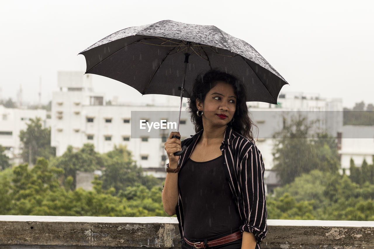 Portrait of beautiful indian girl , wearing balck clothes, enjyoing rain