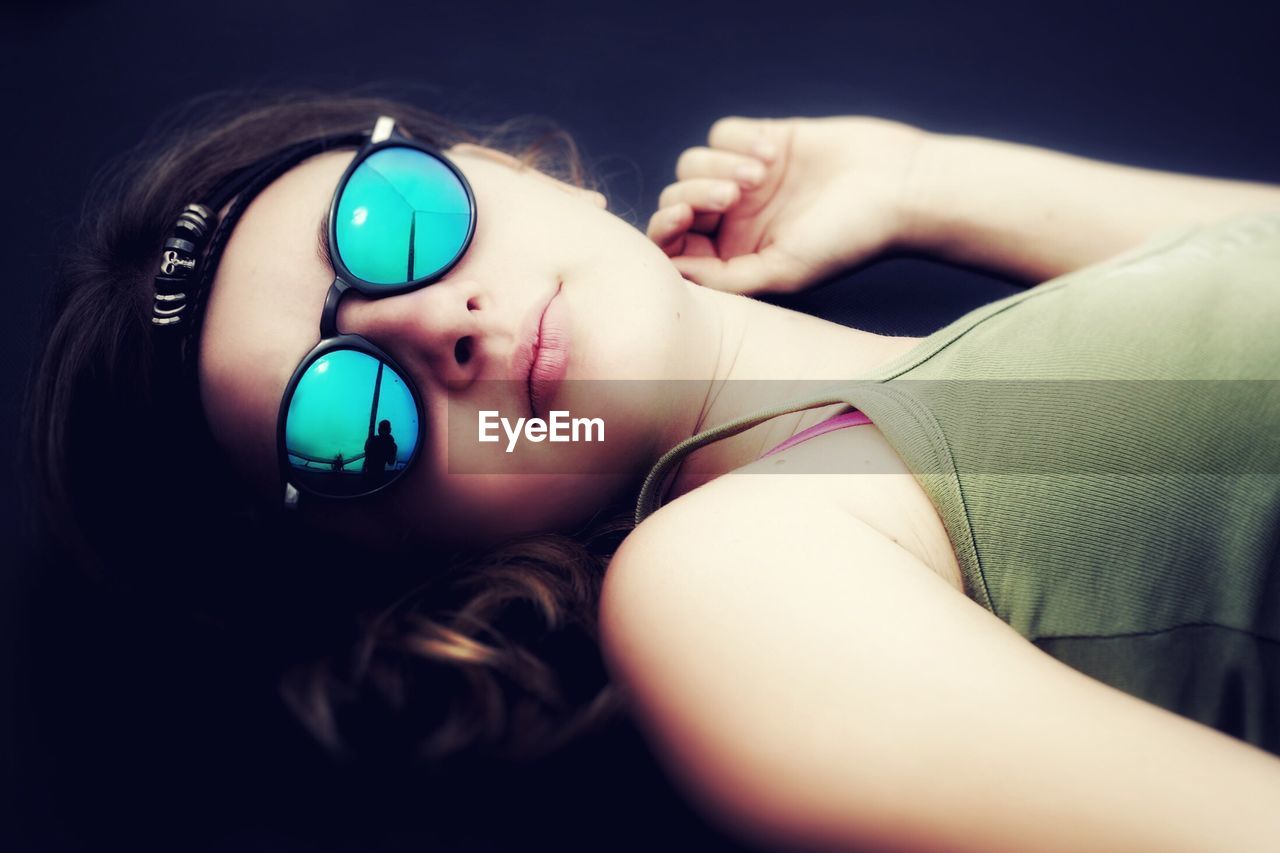 Close-up of teenage girl wearing sunglasses while lying outdoors
