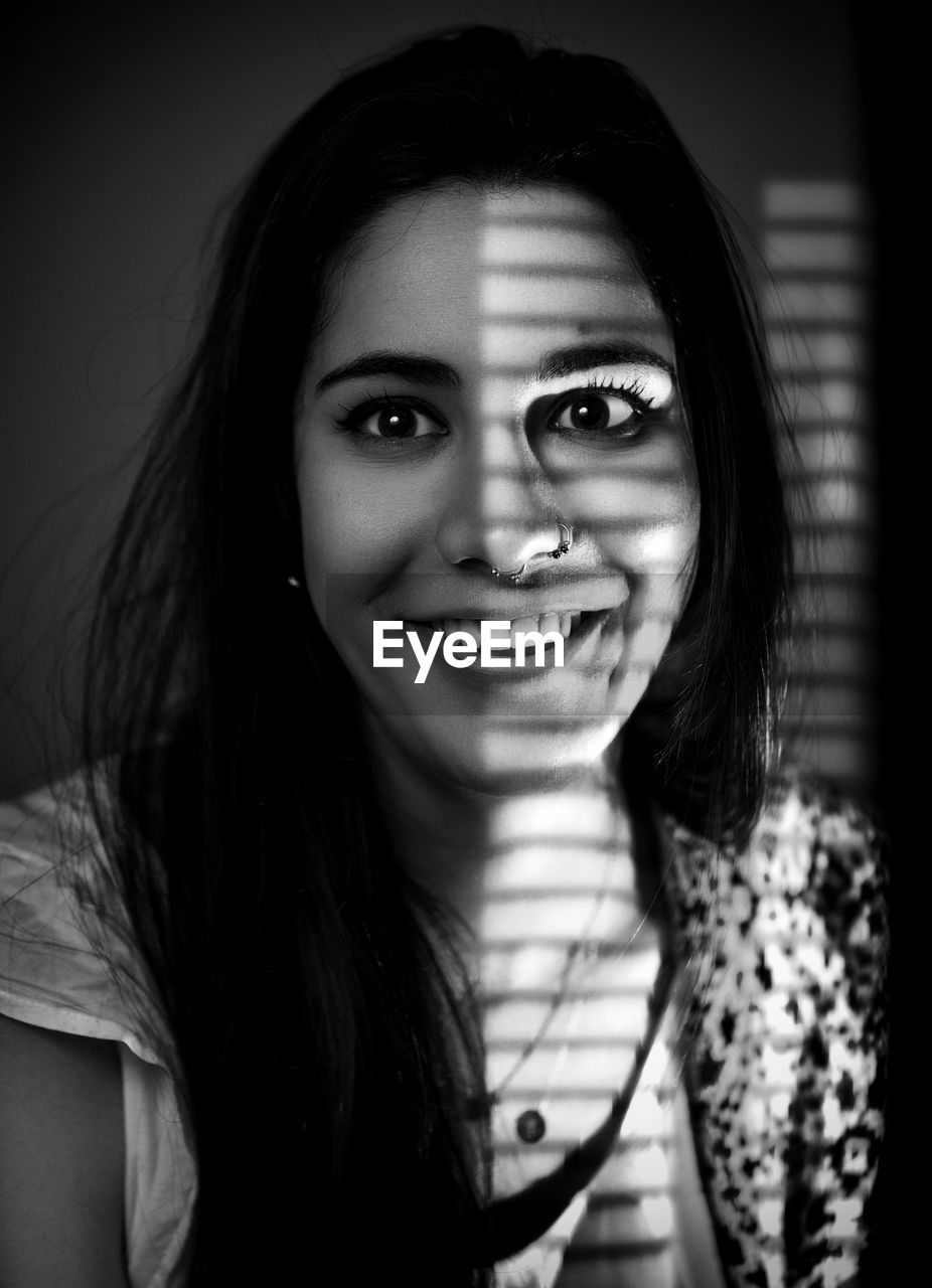 Portrait of smiling young woman with shadow on face