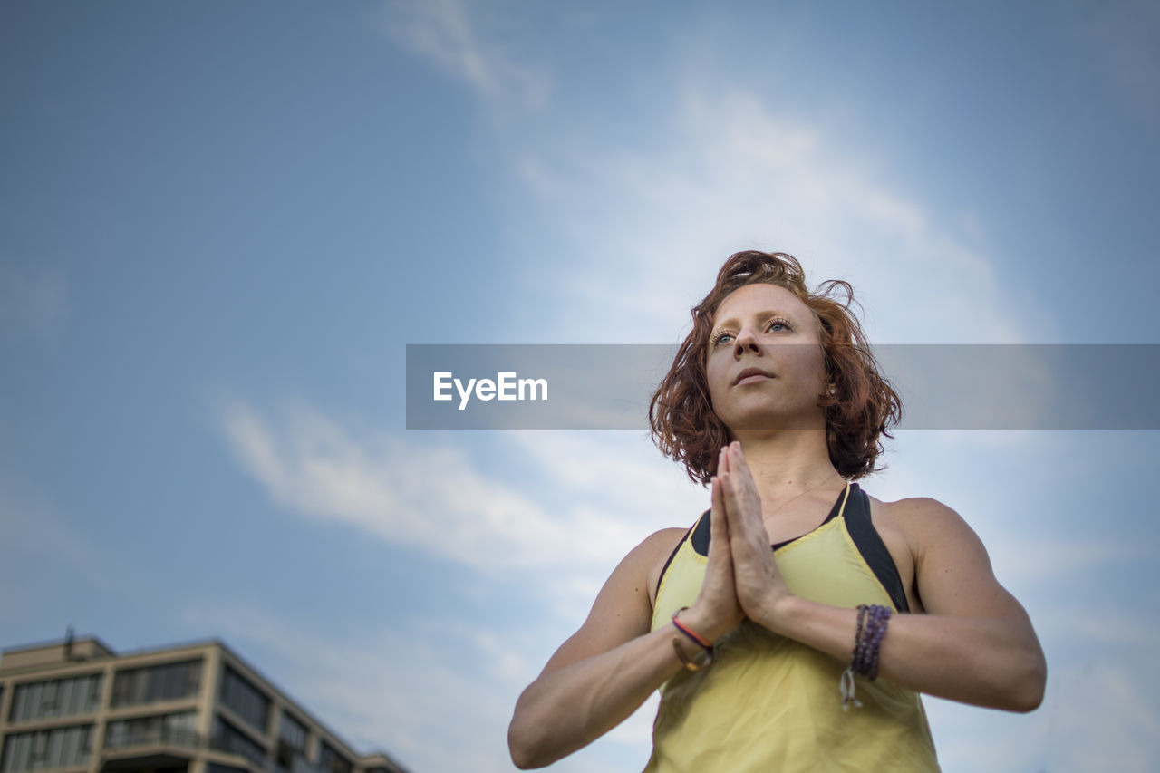 Woman exercising against sky