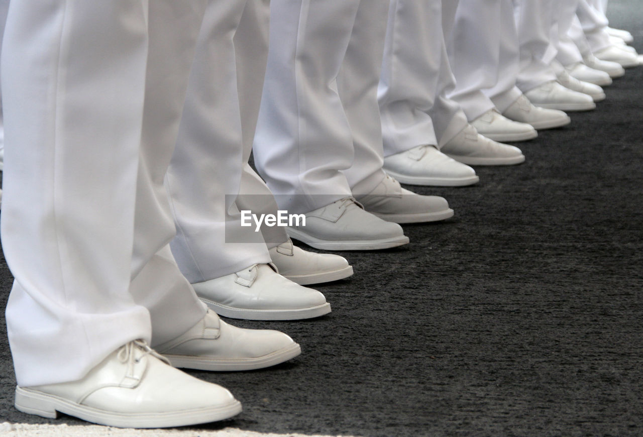 Legs in formation of navy officers white vests and white shoes in perspective