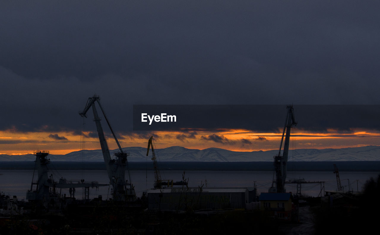 SILHOUETTE CRANES AGAINST SKY DURING SUNSET