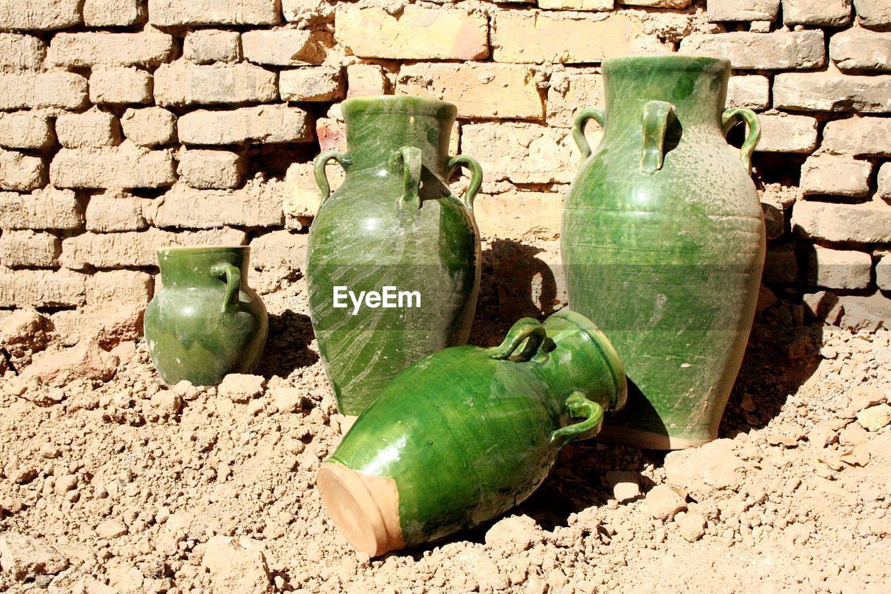 High angle view of old green jars against brick wall
